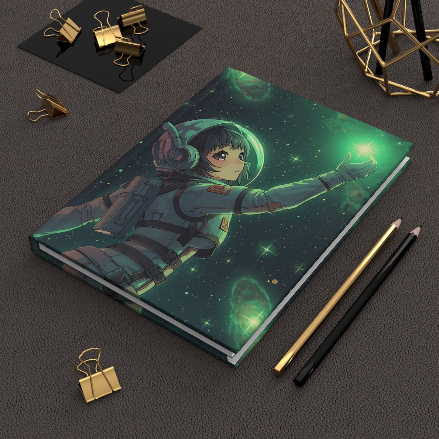 Notebook with space-themed design featuring an astronaut on a dark surface with stationery items.