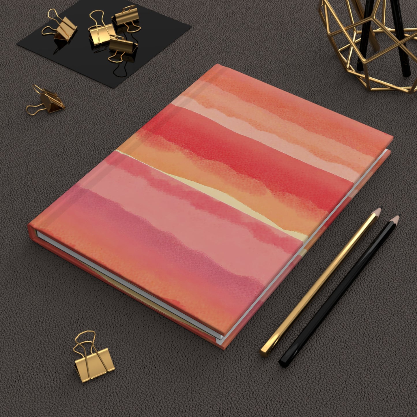 Notebook with a colorful cover on a dark surface with office supplies.