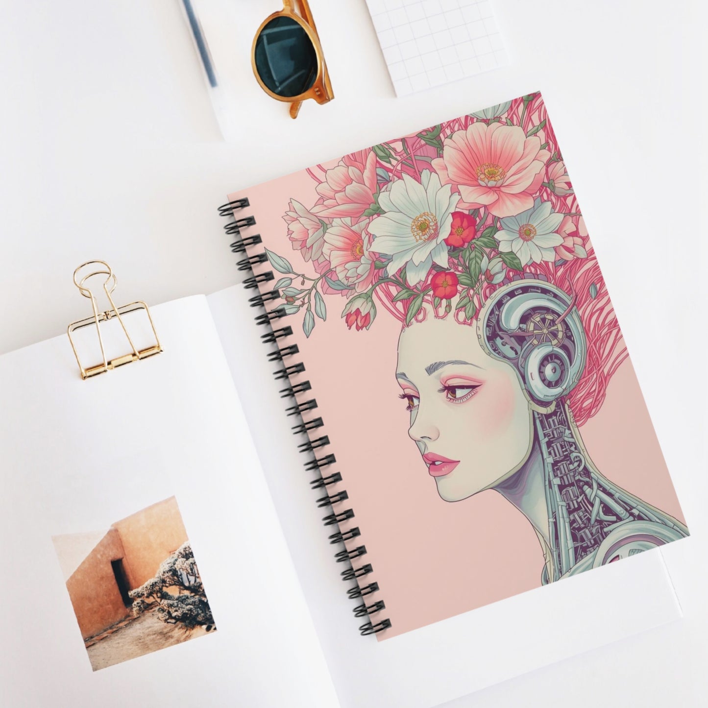 Notebook with floral and portrait design on a white surface, cyberpunk style.