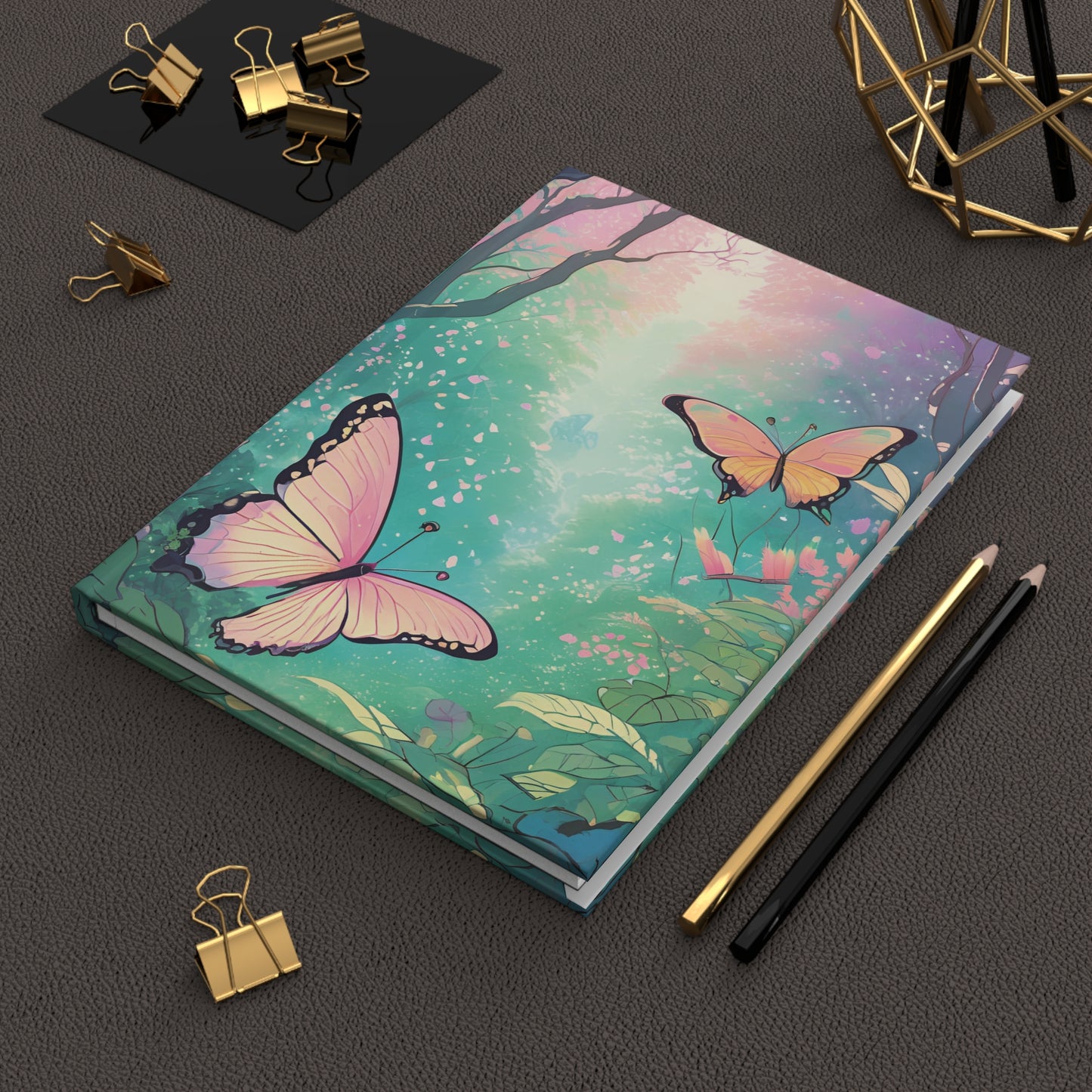 Notebook with butterfly design on a dark surface with stationery items.