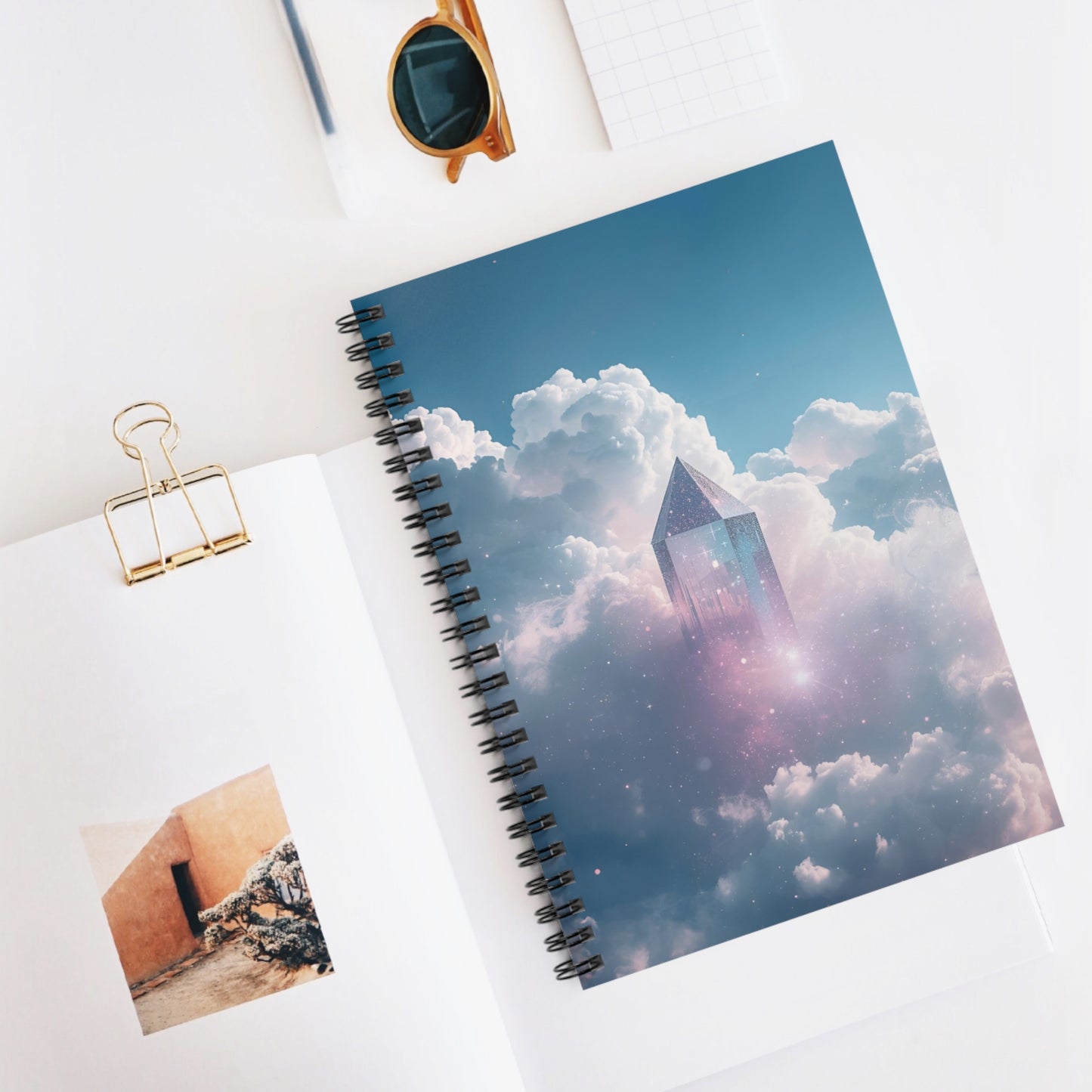 Spiral-bound notebook with a cloud and tower design on a white surface