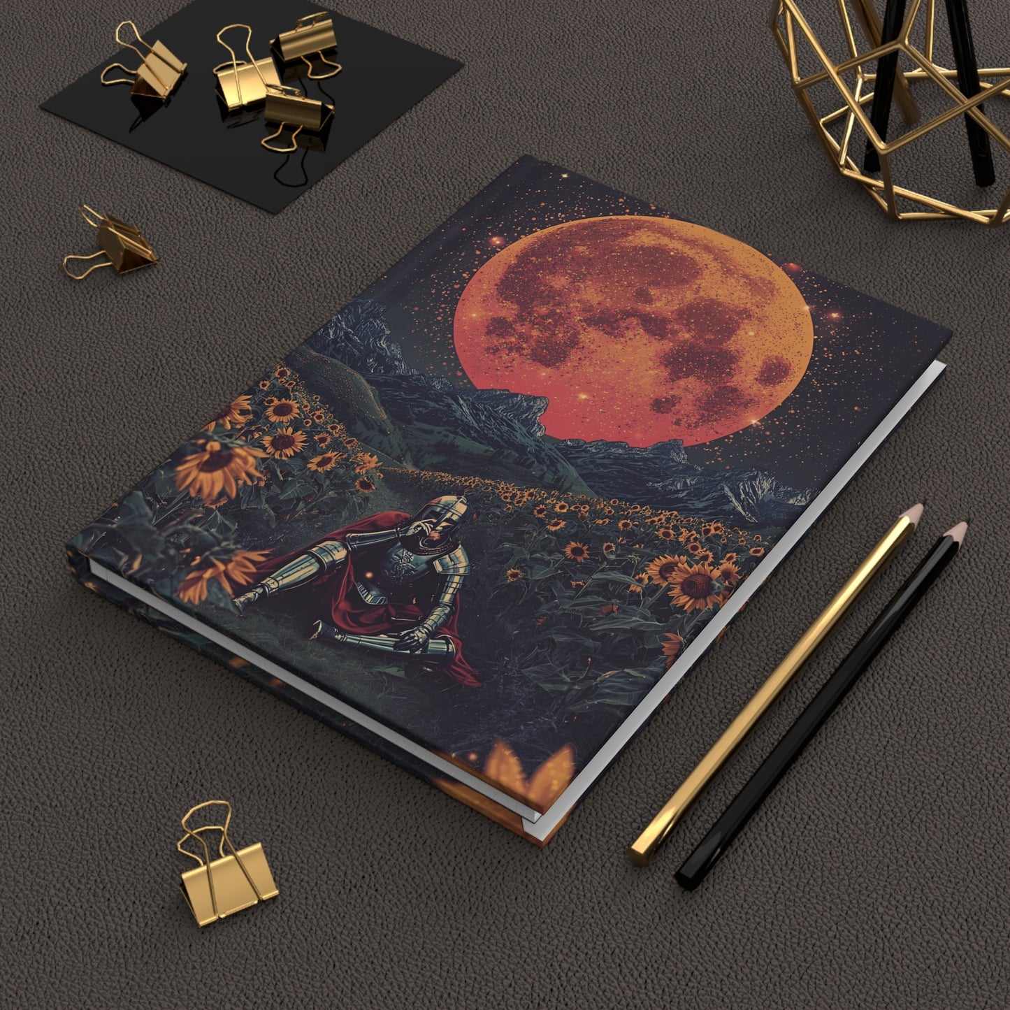 Notebook with a celestial design on a dark surface with stationery items.