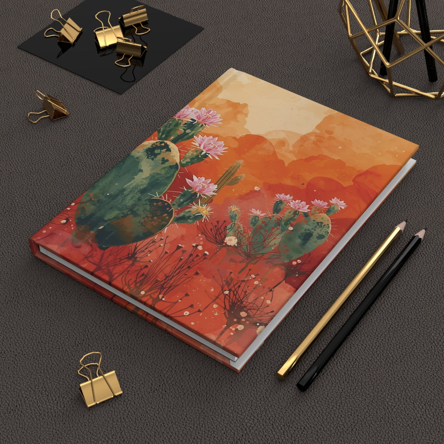Notebook with cactus design on a dark surface with office supplies
