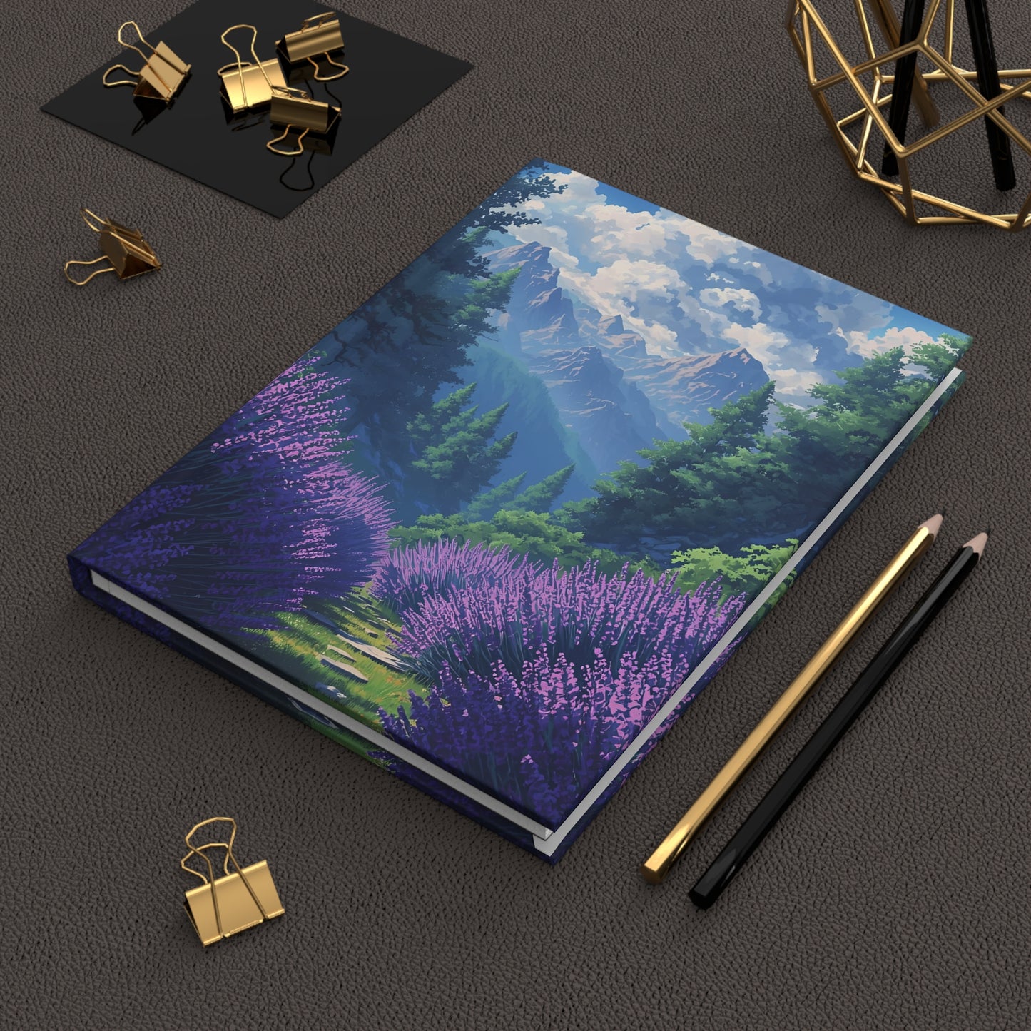 Notebook with mountain and lavender design on a dark surface with office supplies.