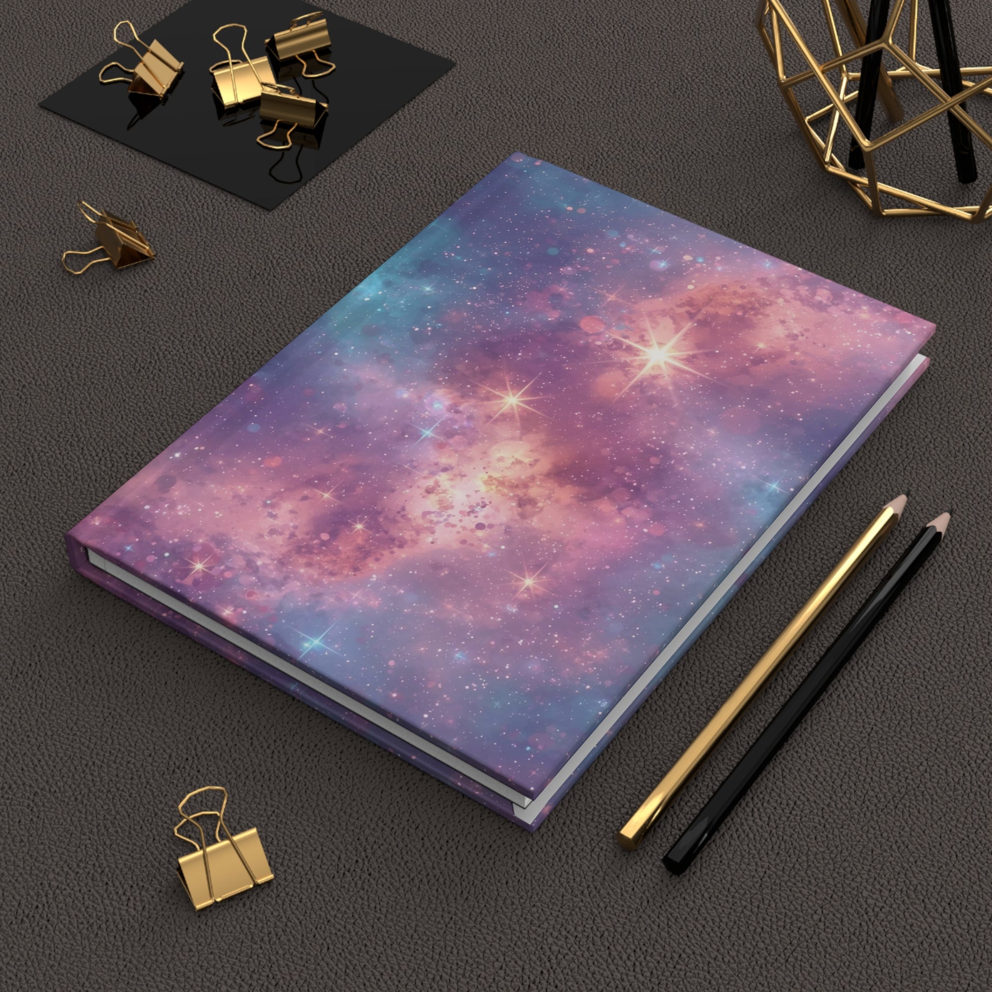 Notebook with galaxy design on a dark surface with office supplies