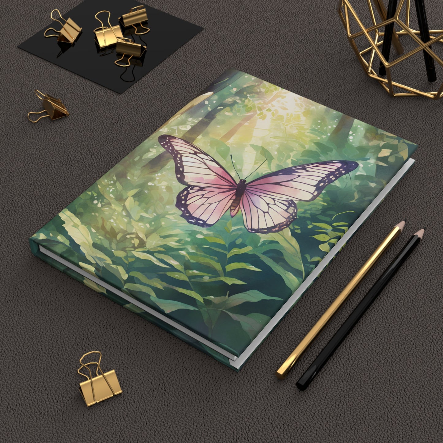 Notebook with a butterfly design on a dark surface with stationery items.