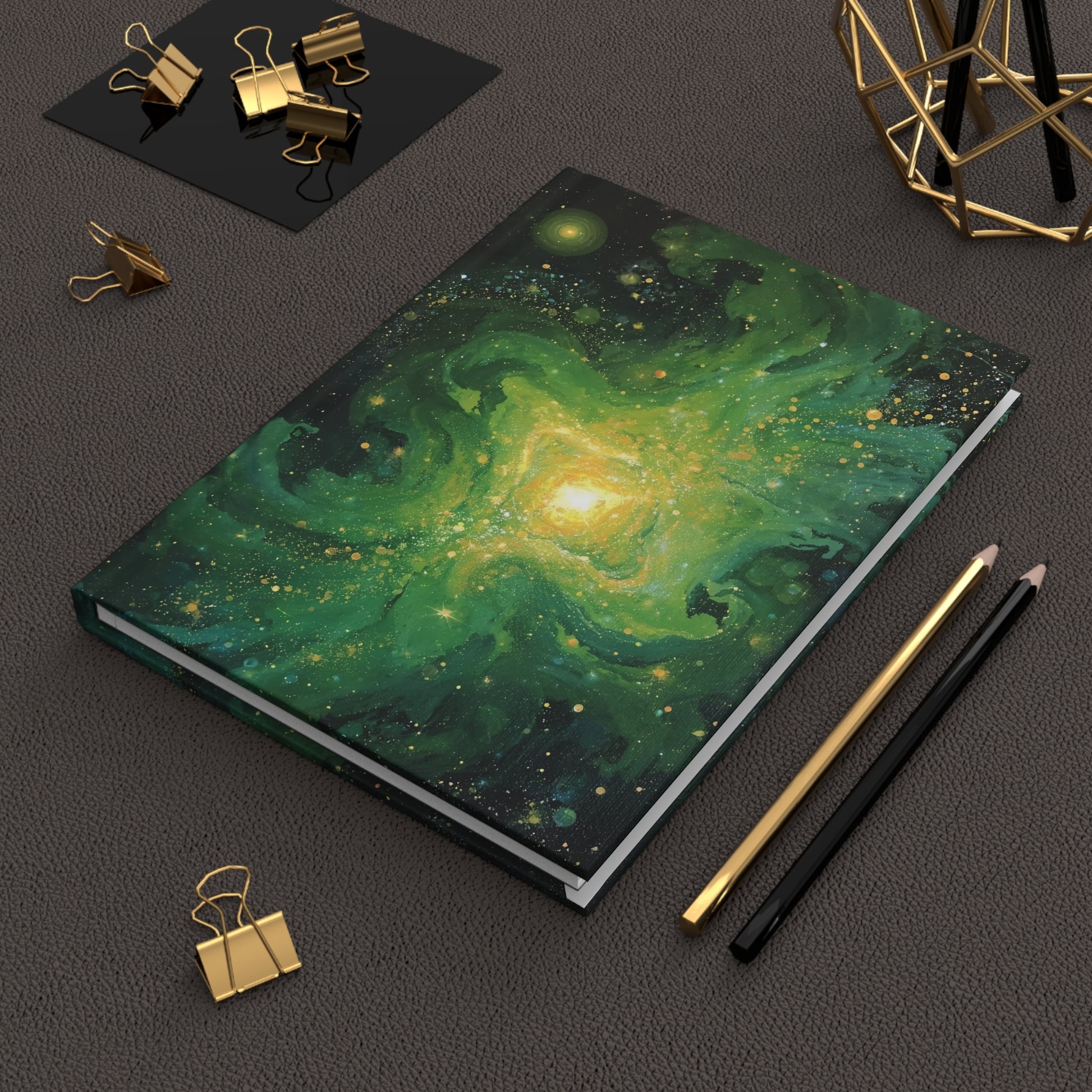 Notebook with galaxy design on a dark surface with stationery items