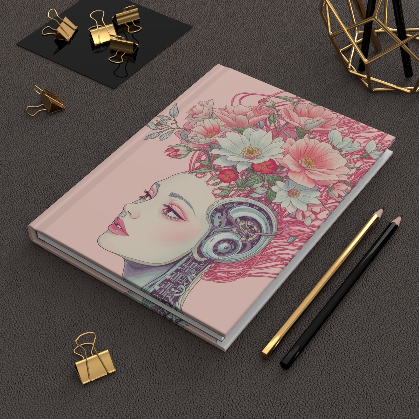 Cyberpunk hardcover notebook with floral and face design on a dark surface with stationery items.