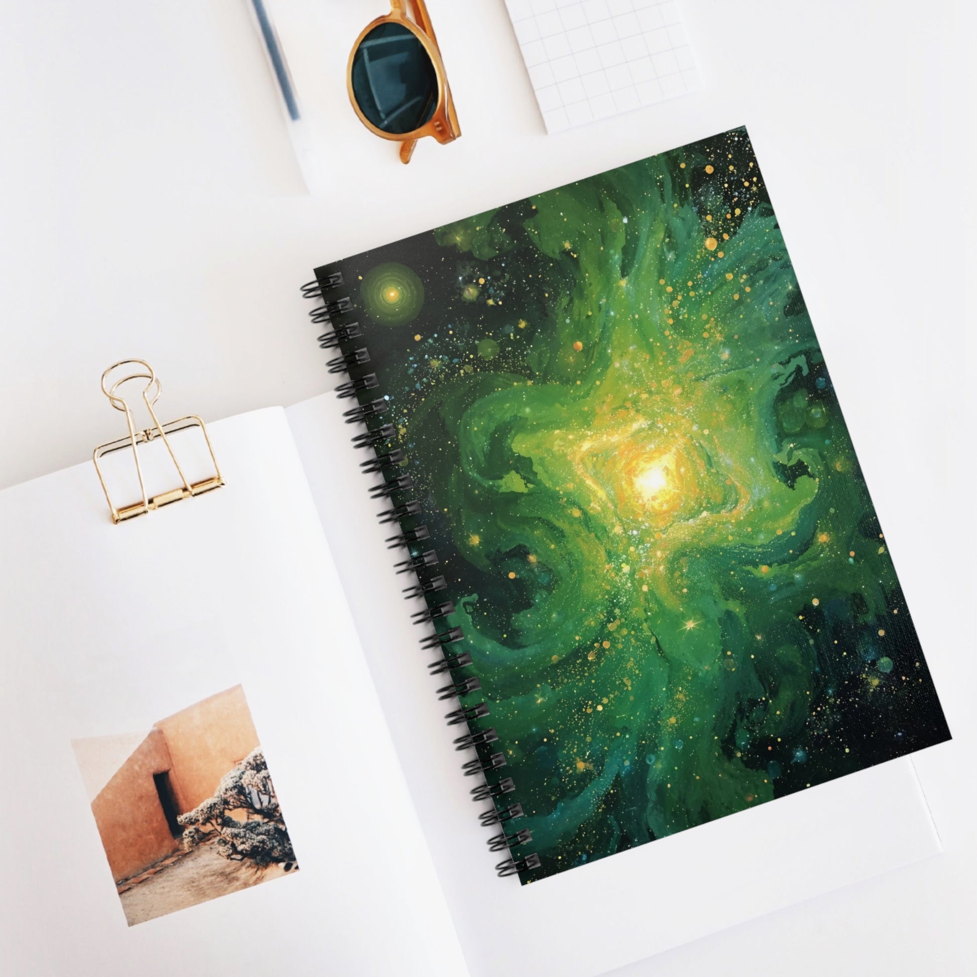Notebook with galaxy design on a white surface with a photo and clip.