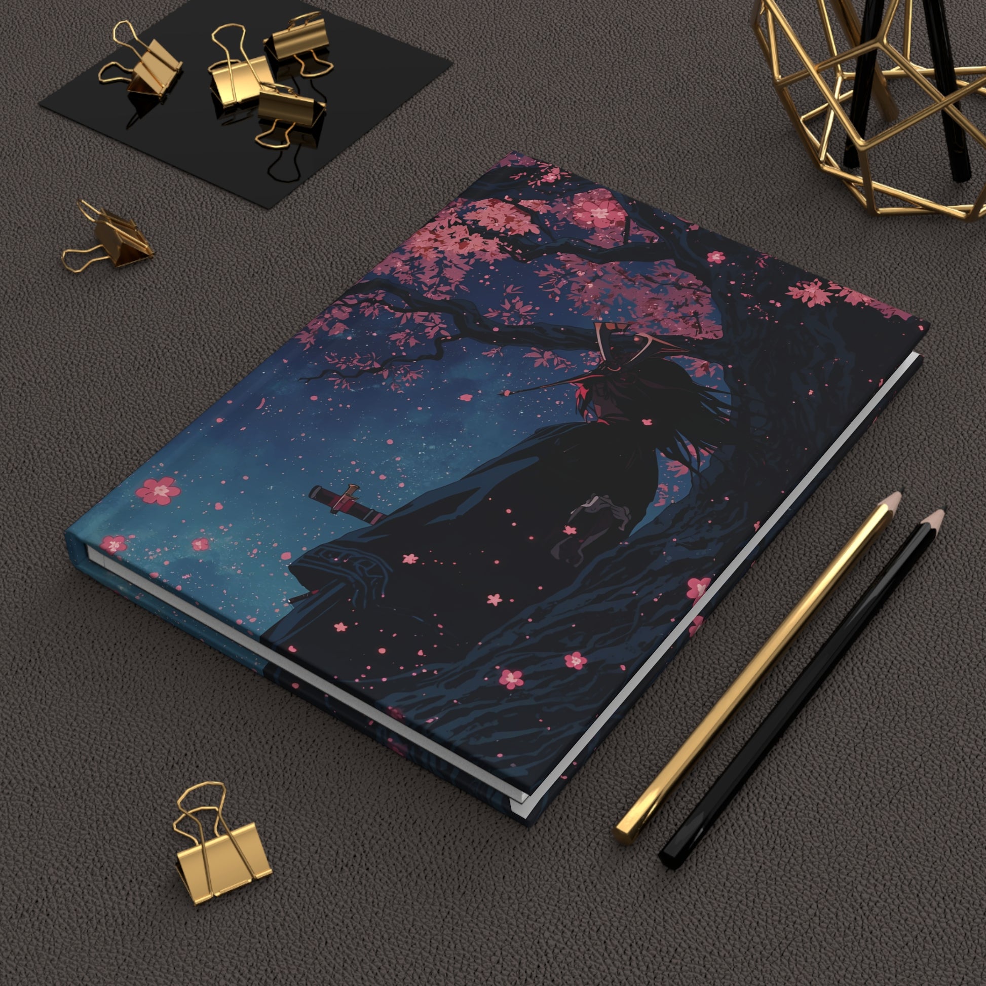 Notebook with artistic cover design on a dark surface with stationery items.