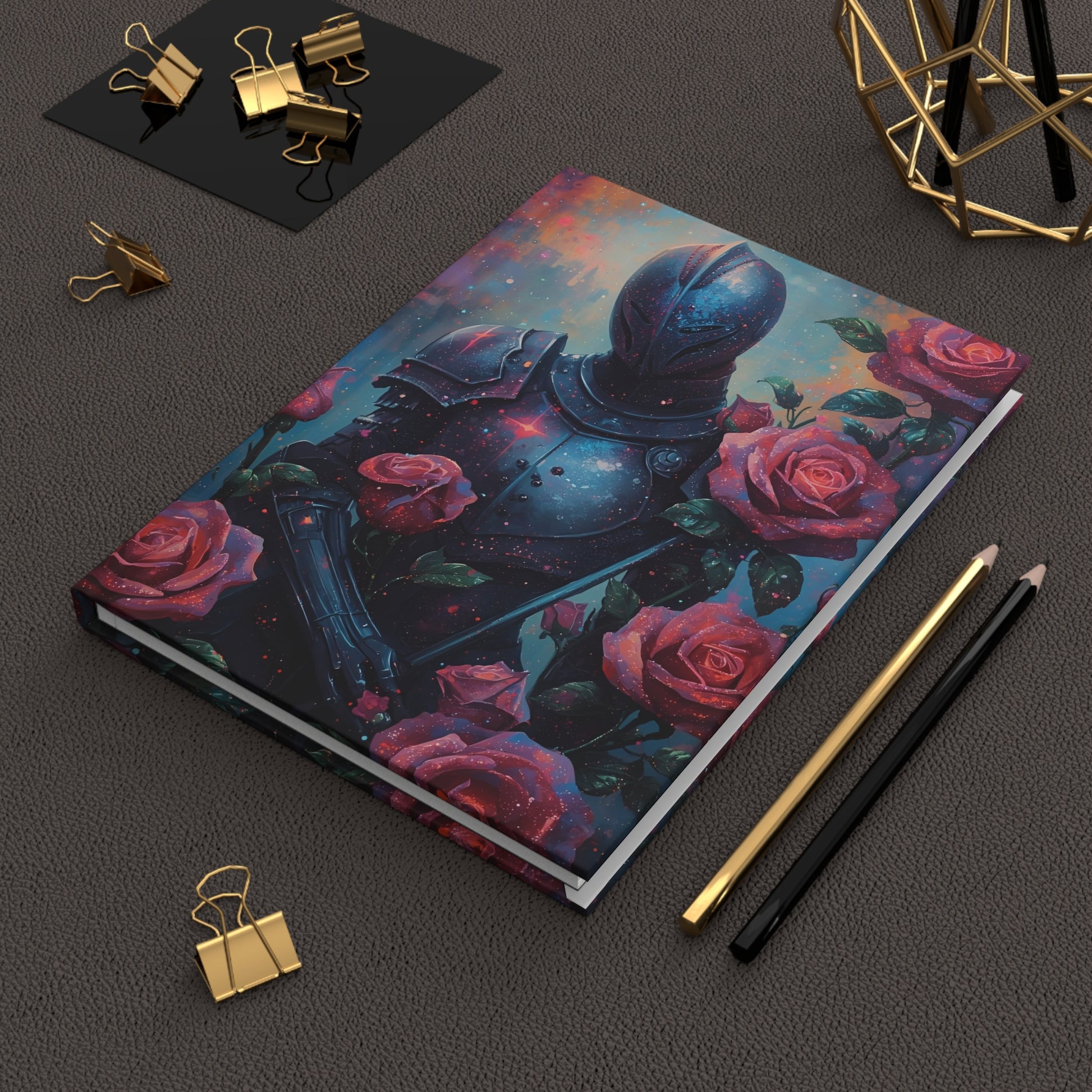 Notebook with a space-themed cover featuring a helmet and roses on a dark surface with stationery items.