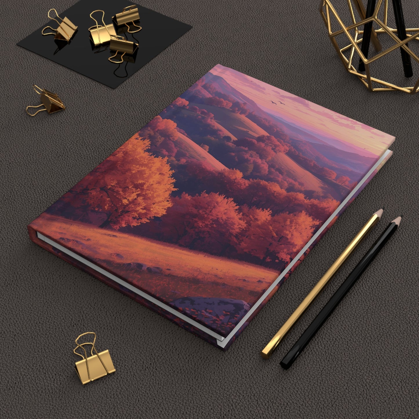 Notebook with a scenic cover on a dark surface with stationery items.