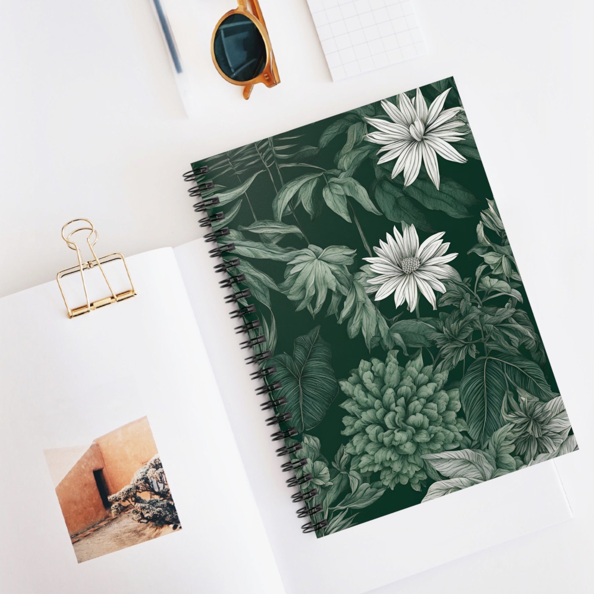 Notebook with floral design on a white surface with a photo and clip.